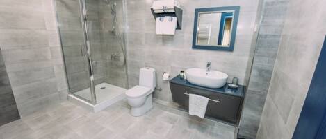 Un baño moderno con cabina de ducha de vidrio, inodoro, lavabo y espejo.