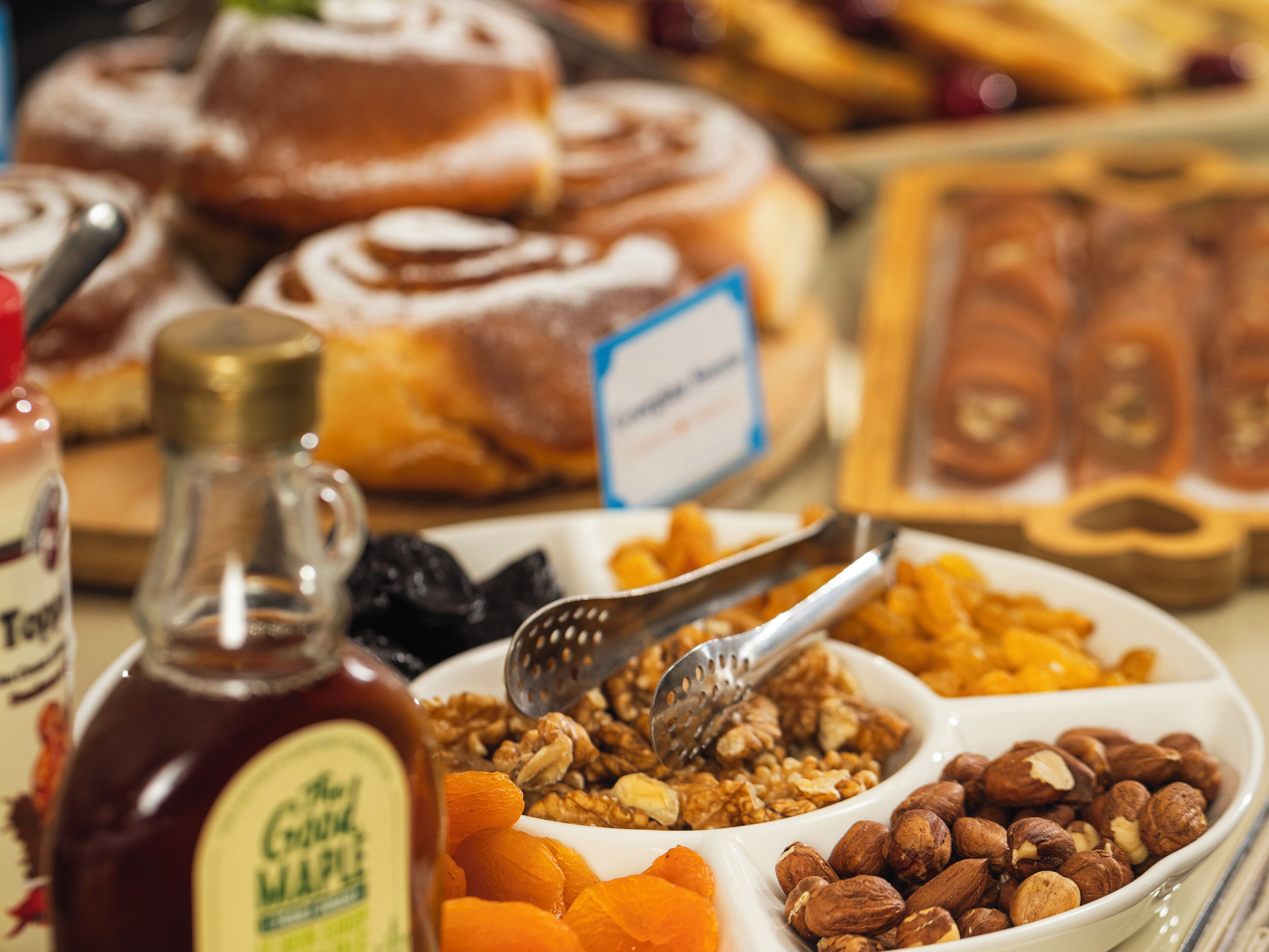 A table with various food items including a bottle of syrup, nuts, dried fruits, and pastries.