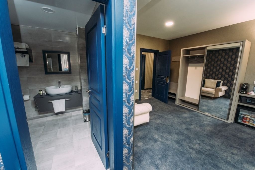 Un baño moderno con un espejo grande, tocador con lavabo y vestidor con espejo.
