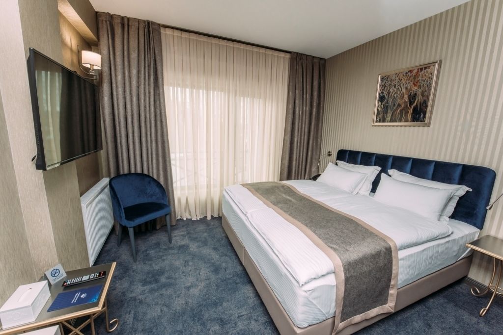 Une chambre d’hôtel avec un grand lit, un bureau avec un ordinateur, une chaise et un téléviseur.