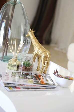 A table with a decorative glass vase, a golden giraffe figurine, a small glass terrarium, and a bowl of candy.