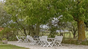 An outdoor seating area with a table and chairs under a tree. - Ljungs Fem Rum (Gotlands Tofta)