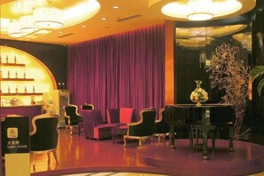 A lobby with a reception desk, seating area, and a decorative plant. - Oceanwide Hotel (Weifang)