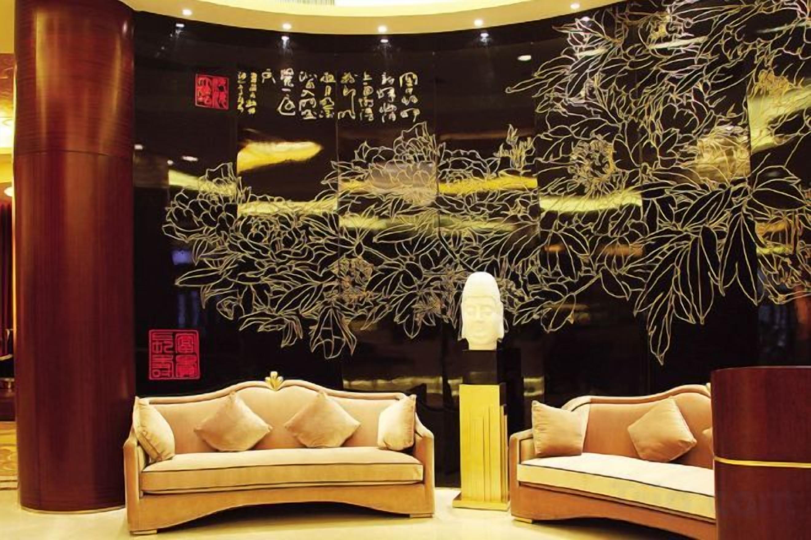 A lobby with two sofas, a large decorative tree sculpture, and a bust on a pedestal.