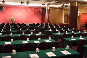 Un salón de conferencias con filas de mesas, cada una con un calentador de agua y un bloc de notas.
