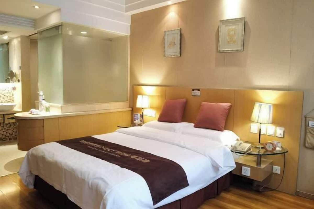 Une chambre d’hôtel comprenant un lit, des tables de chevet, un miroir et une salle de bain.