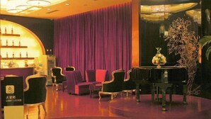 A lobby with a curved seating area, a bar with bottles, and a decorative plant. - Oceanwide Hotel (Weifang)