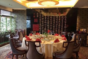 A dining area with round tables set for a meal, surrounded by chairs. - Oceanwide Hotel (Weifang)