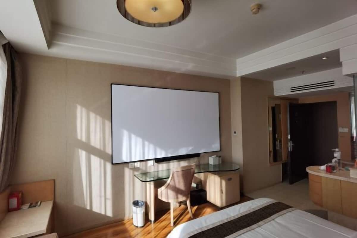 Une chambre d’hôtel comprenant un lit, un bureau avec une chaise, une télévision et un minibar.