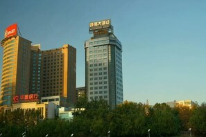 Un paisaje urbano con edificios altos, incluyendo un hotel con un letrero rojo llamativo y otro con un letrero azul.