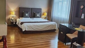 A hotel room with a large bed, two bedside tables with lamps, a desk with a chair, and a large window with curtains. - Oceanwide Hotel (Weifang)