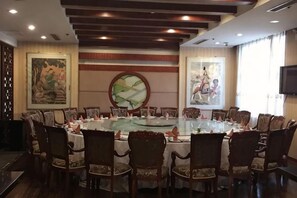 Un salón de conferencias con una mesa redonda, sillas y obras de arte en las paredes.