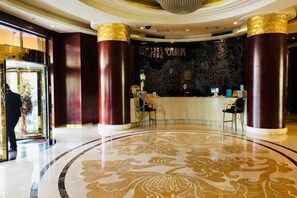 A hotel lobby with a reception desk, large columns, and a patterned floor. - Oceanwide Hotel (Weifang)