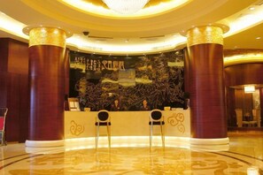 A reception area with two chairs, a reception desk, and a decorative wall with artwork. - Oceanwide Hotel (Weifang)