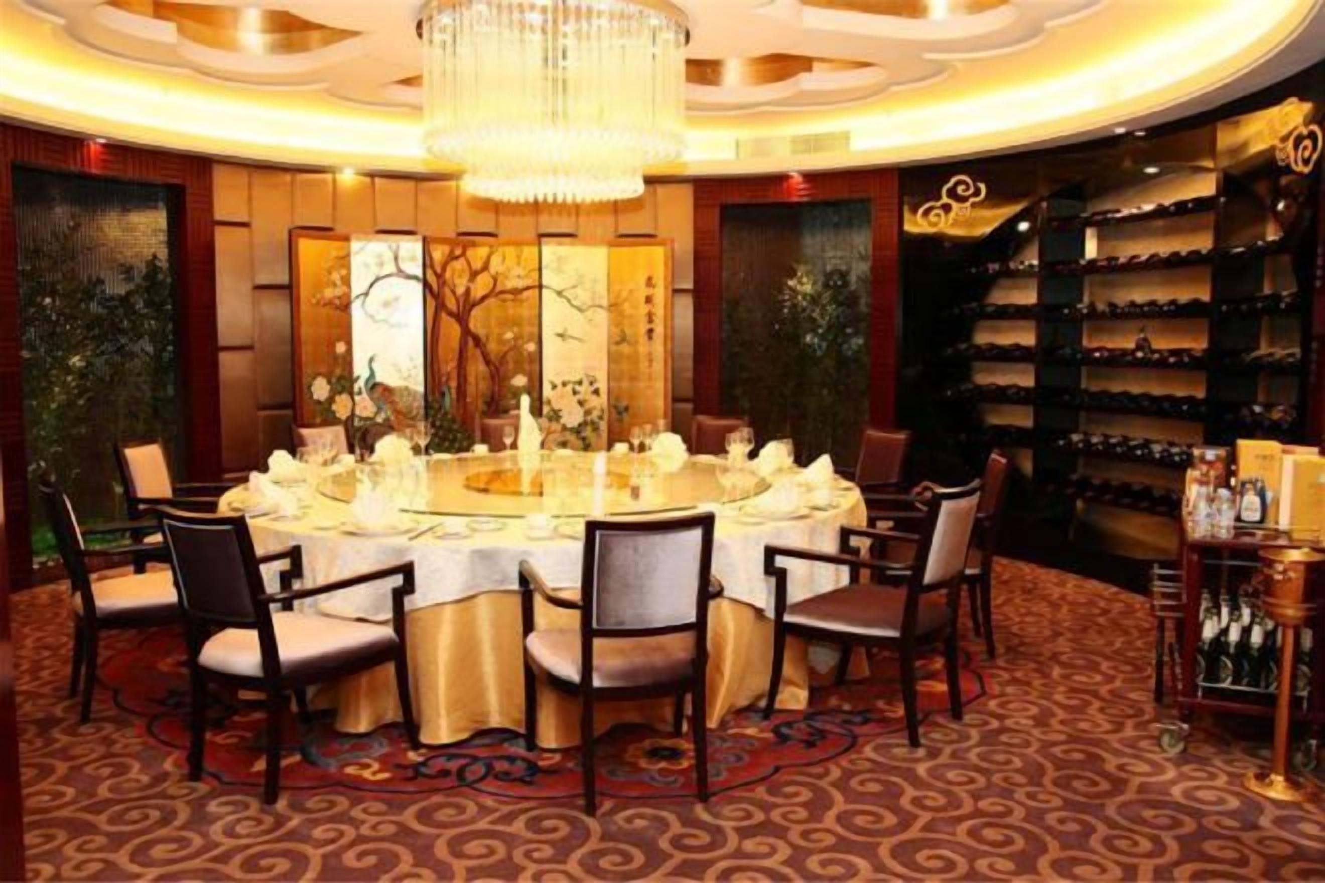 A formal dining room with a round table, chairs, and a chandelier.