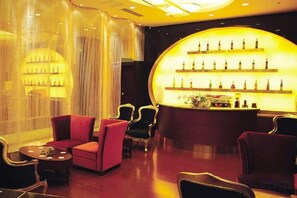 Una zona de bar con asientos y una exhibición de botellas.