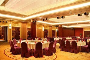 A banquet hall with round tables, chairs, and a carpeted floor. - Oceanwide Hotel (Weifang)