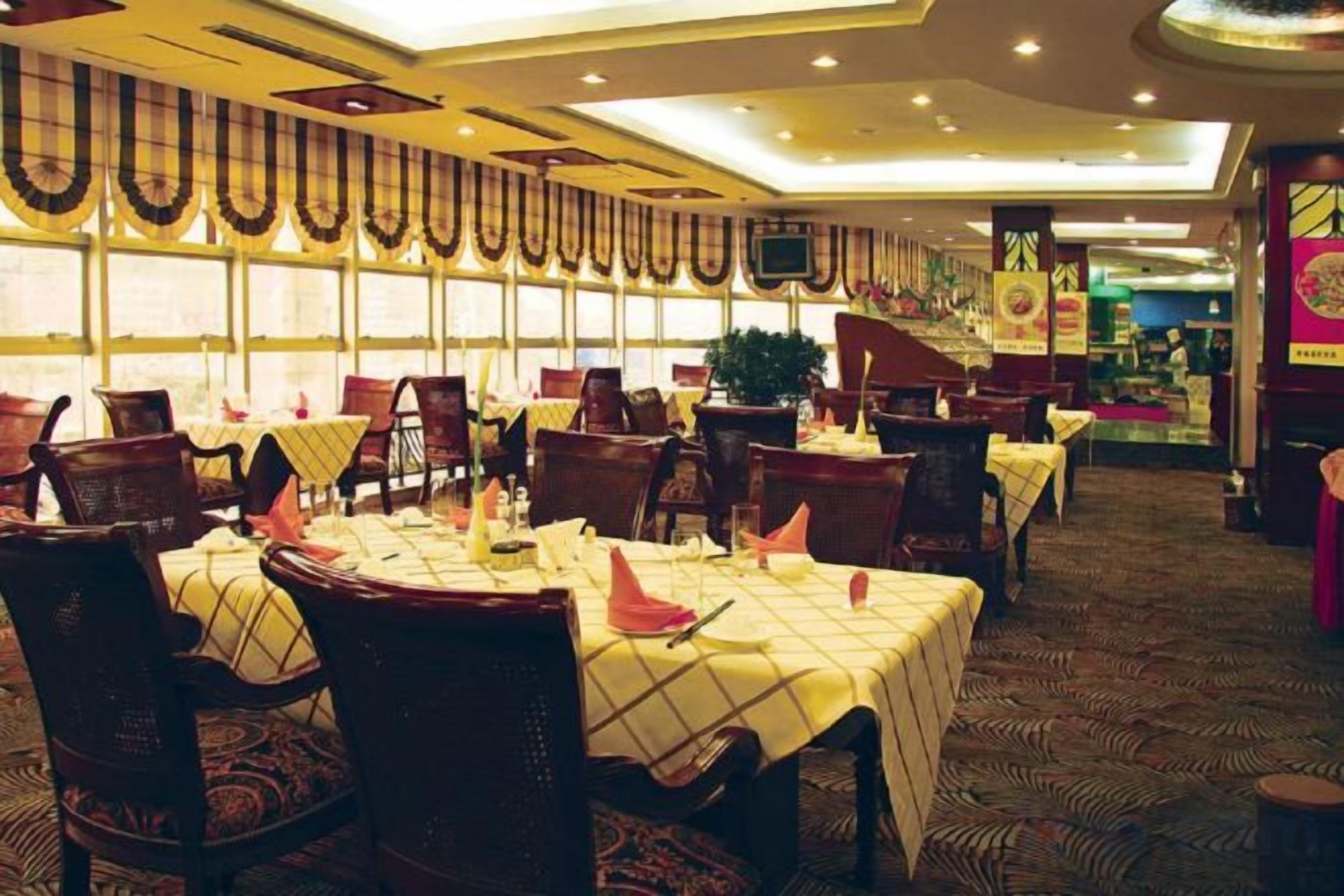 Un restaurante con mesas dispuestas para comer, sillas y una alfombra estampada.