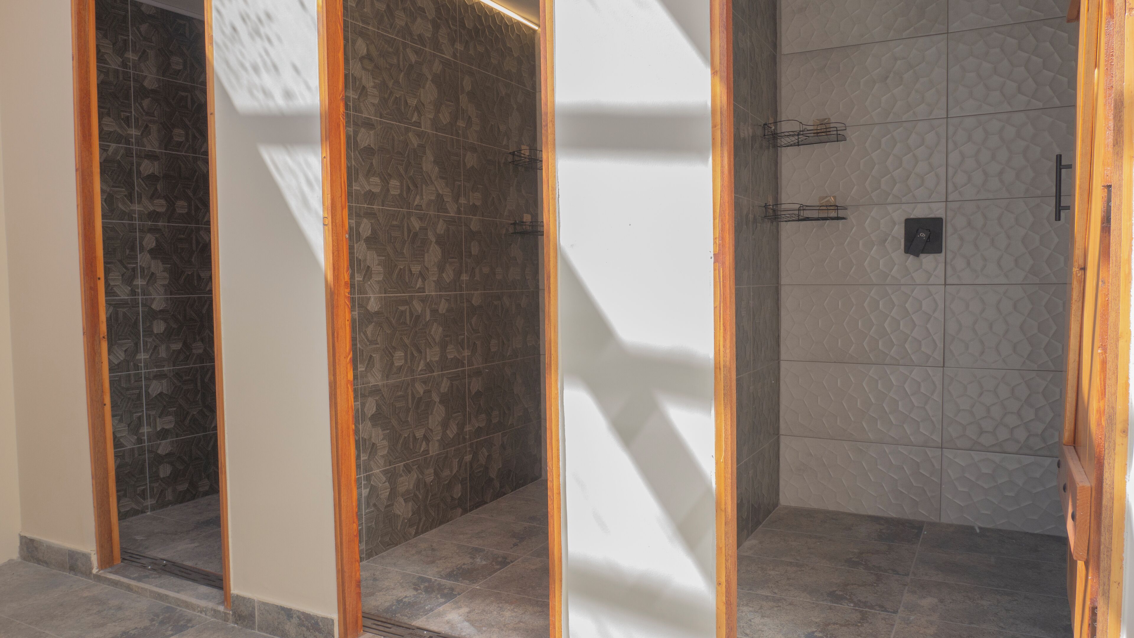 Un baño moderno con cabina de ducha, paredes de azulejos y estructura de madera.