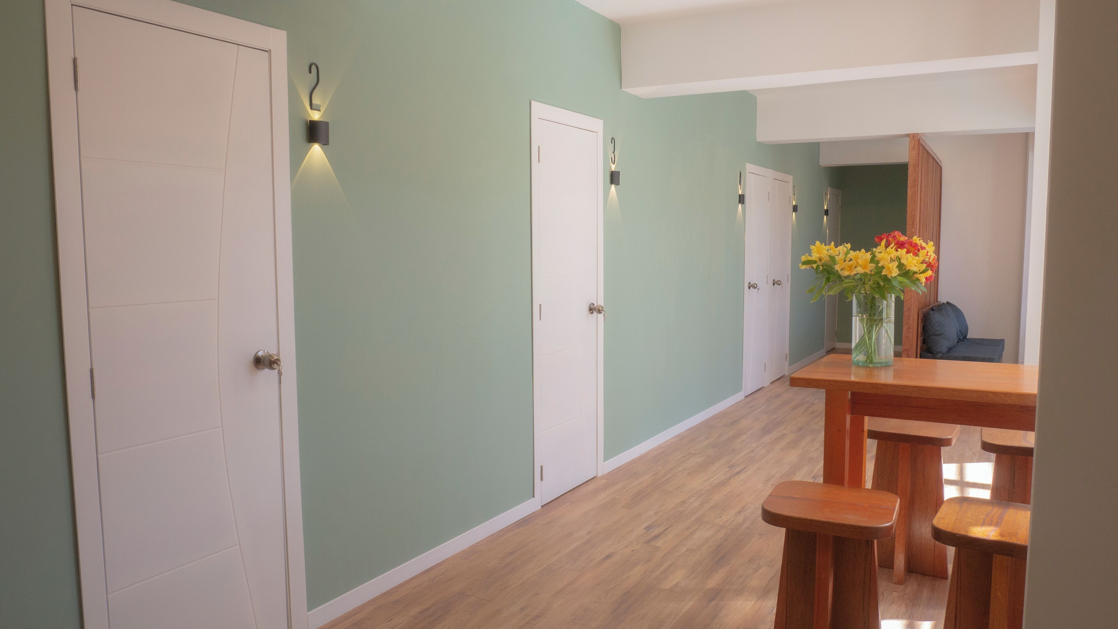 A hallway with white doors, a wooden bench, and a vase with flowers.