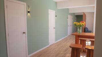 A hallway with white doors, a wooden bench, and a vase with flowers.