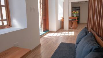 Uma sala de estar moderna com um banco de madeira, um sofá e uma área de jantar com mesa e cadeiras.
