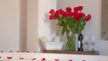 Una estantería con un jarrón de rosas rojas, una botella de vino y dos copas de vino.
