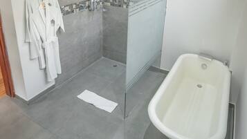 A bathroom with a bathtub, a shower, and a towel rack with towels.