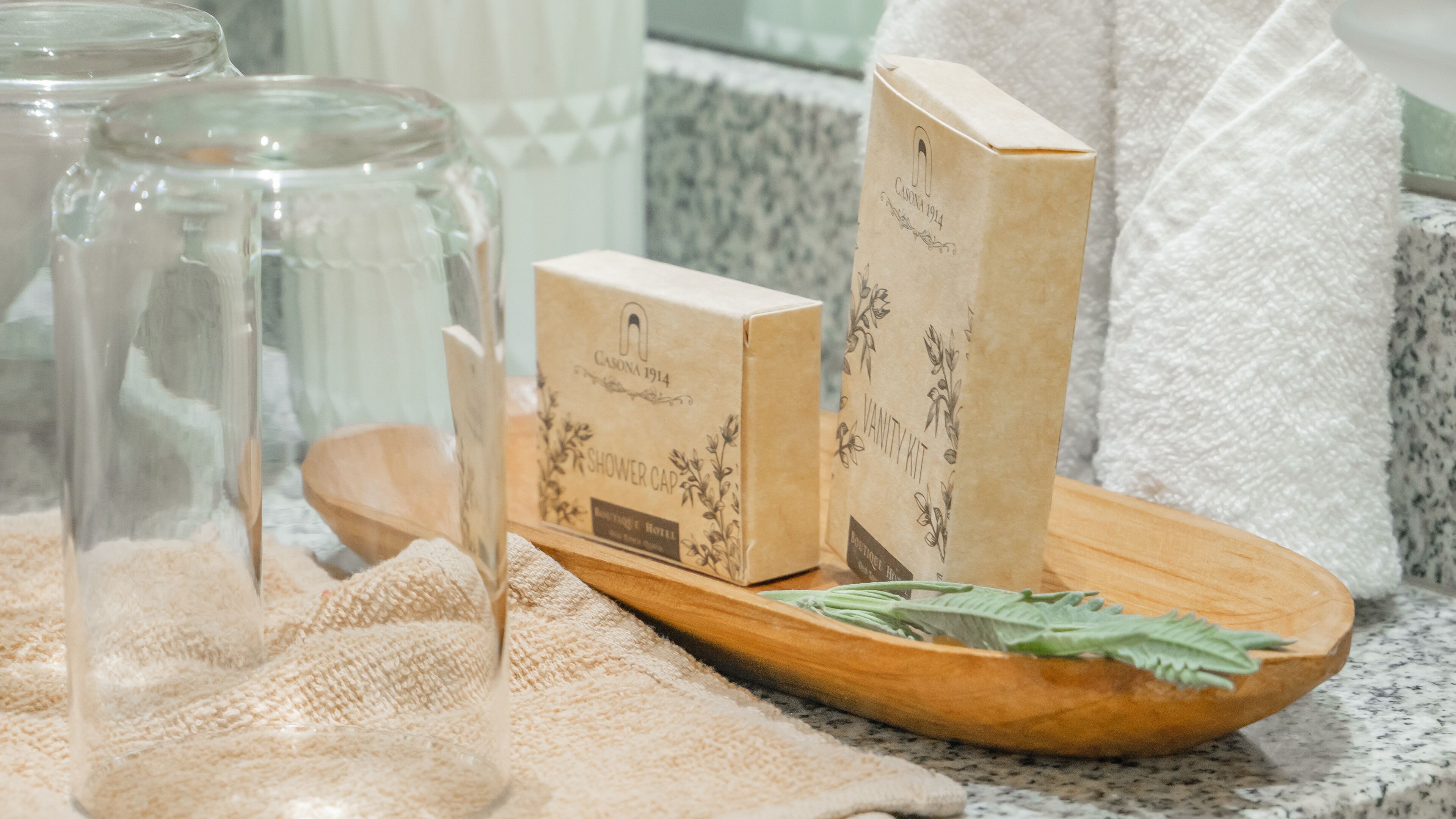 A wooden tray with a shower cap and a vanity kit on a textured surface.