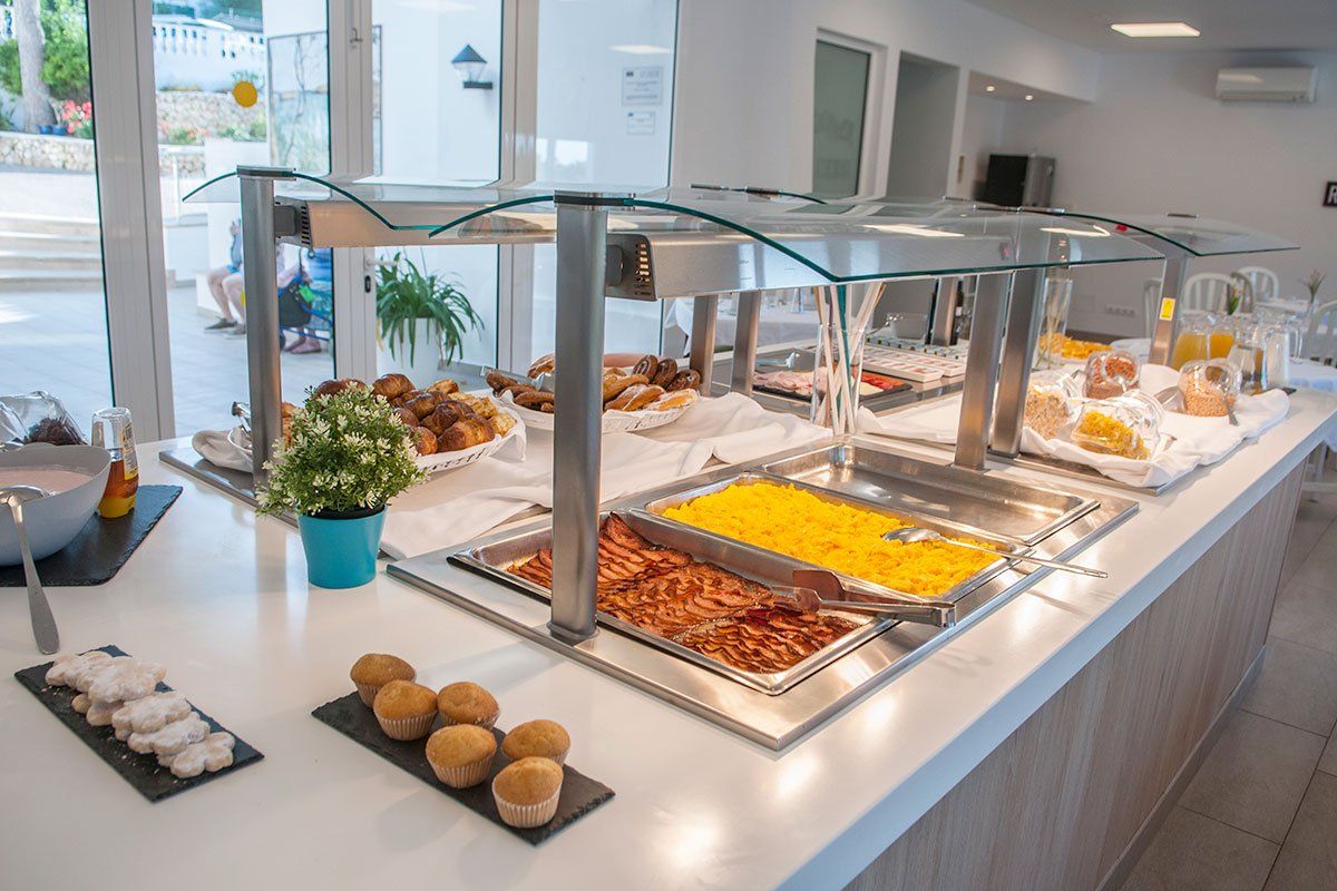 Un bufé con diversos alimentos, como pasteles, carnes y frutas.