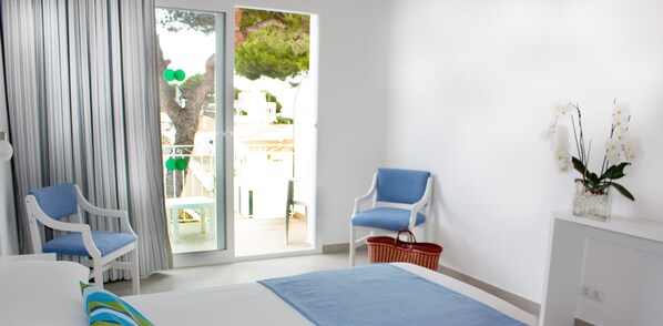 A bedroom with a bed, two chairs, a small table, a basket, and a plant. - Xuroy (Sant Lluis)