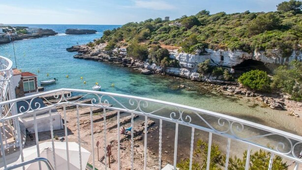 Une vue sur la côte depuis un balcon, avec une eau cristalline, des falaises rocheuses et une végétation luxuriante.