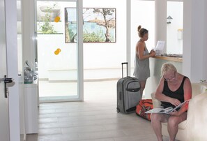 A room with a large window, a sofa, a table, and a suitcase. - Xuroy (Sant Lluis)