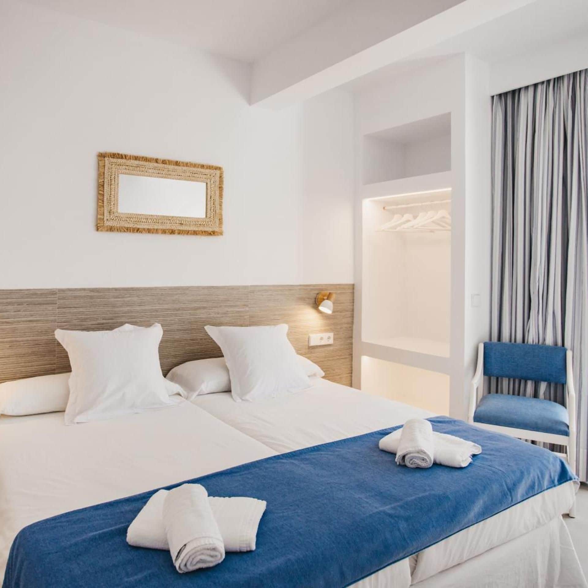 Una habitación de hotel con una cama grande, un espejo, un armario y una silla.