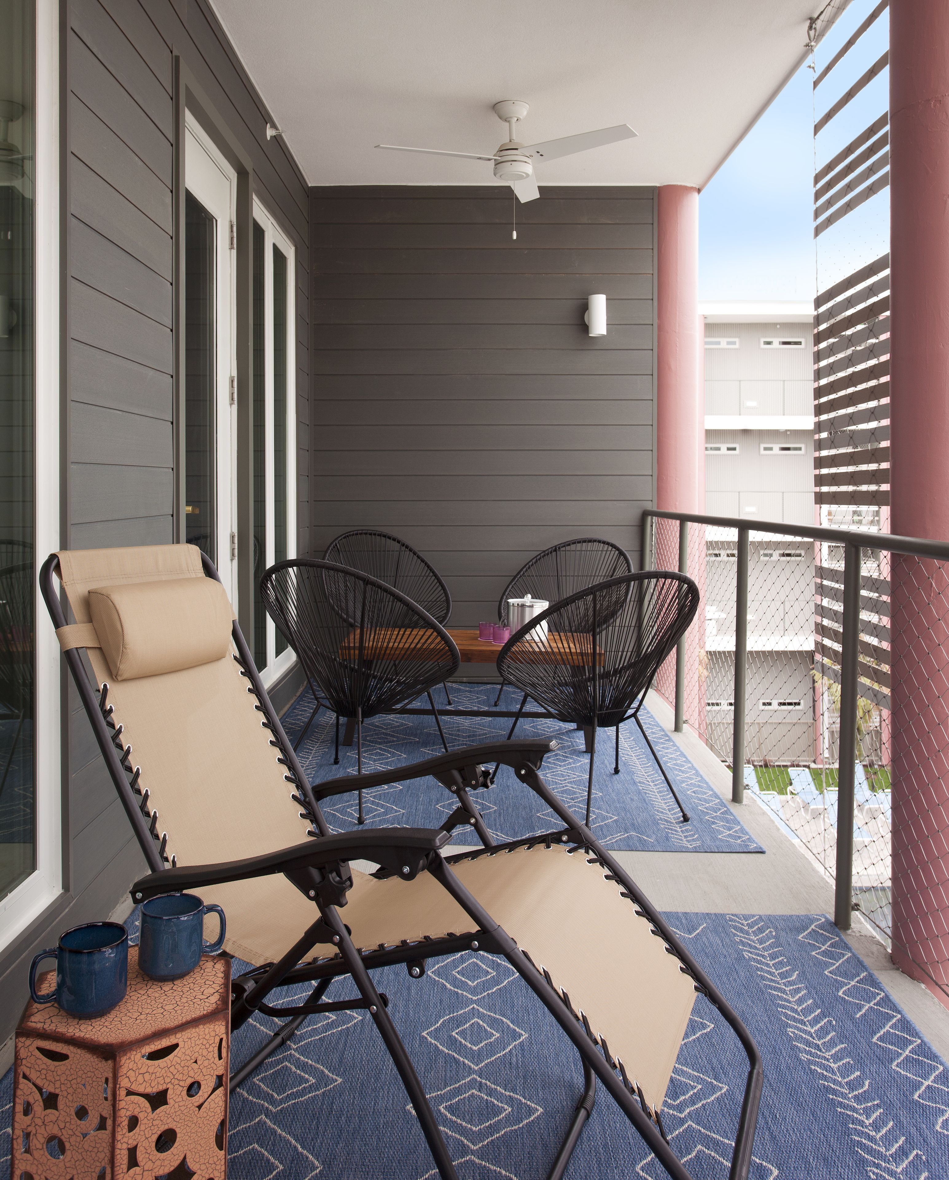 Un balcon doté d’un ventilateur de plafond, de deux fauteuils et d’une table.