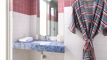 A bathroom with a marble sink, a hanging robe, and pink and white tiles.