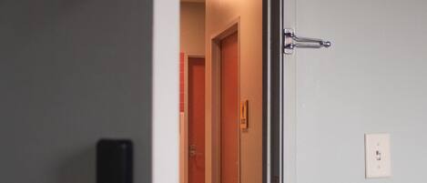 An open door leading to a hallway with a tiled floor and a wooden door in the background.