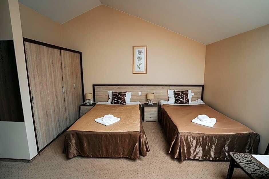 A bedroom with two beds, a wardrobe, a framed picture on the wall, and a small table.