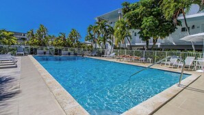 A swimming pool with lounge chairs and umbrellas, surrounded by palm trees and a building with balconies. - Park Royal Miami Beach managed by Accor (Miami Beach)