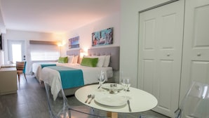 A hotel room with two beds, a dining table set for two, and a large wardrobe. - Park Royal Miami Beach managed by Accor (Miami Beach)