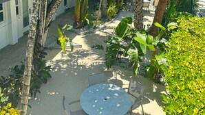 A courtyard with a round table and chairs, surrounded by various tropical plants and trees. - Park Royal Miami Beach managed by Accor (Miami Beach)