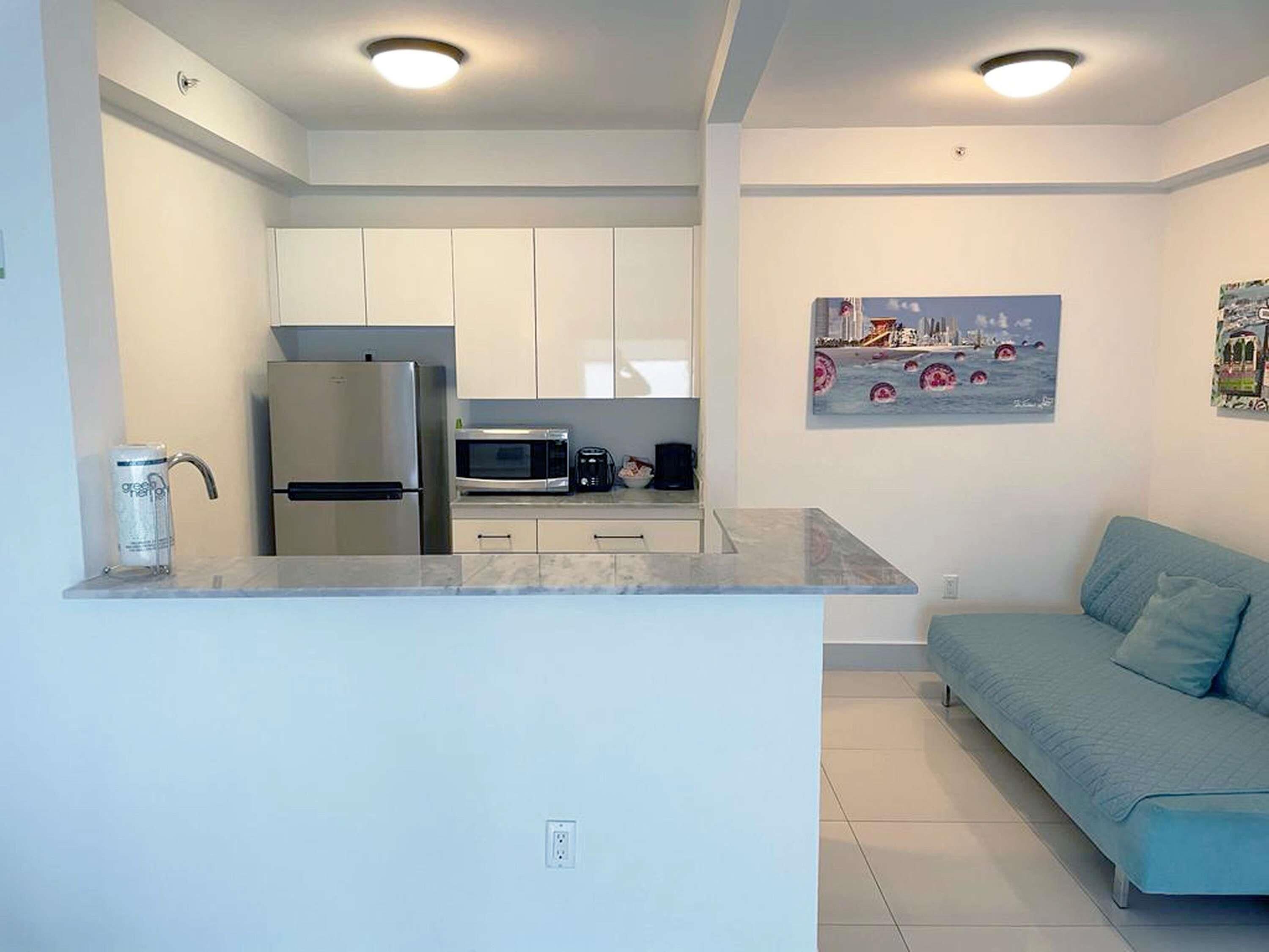 A modern kitchen with a refrigerator, microwave, and a coffee machine.