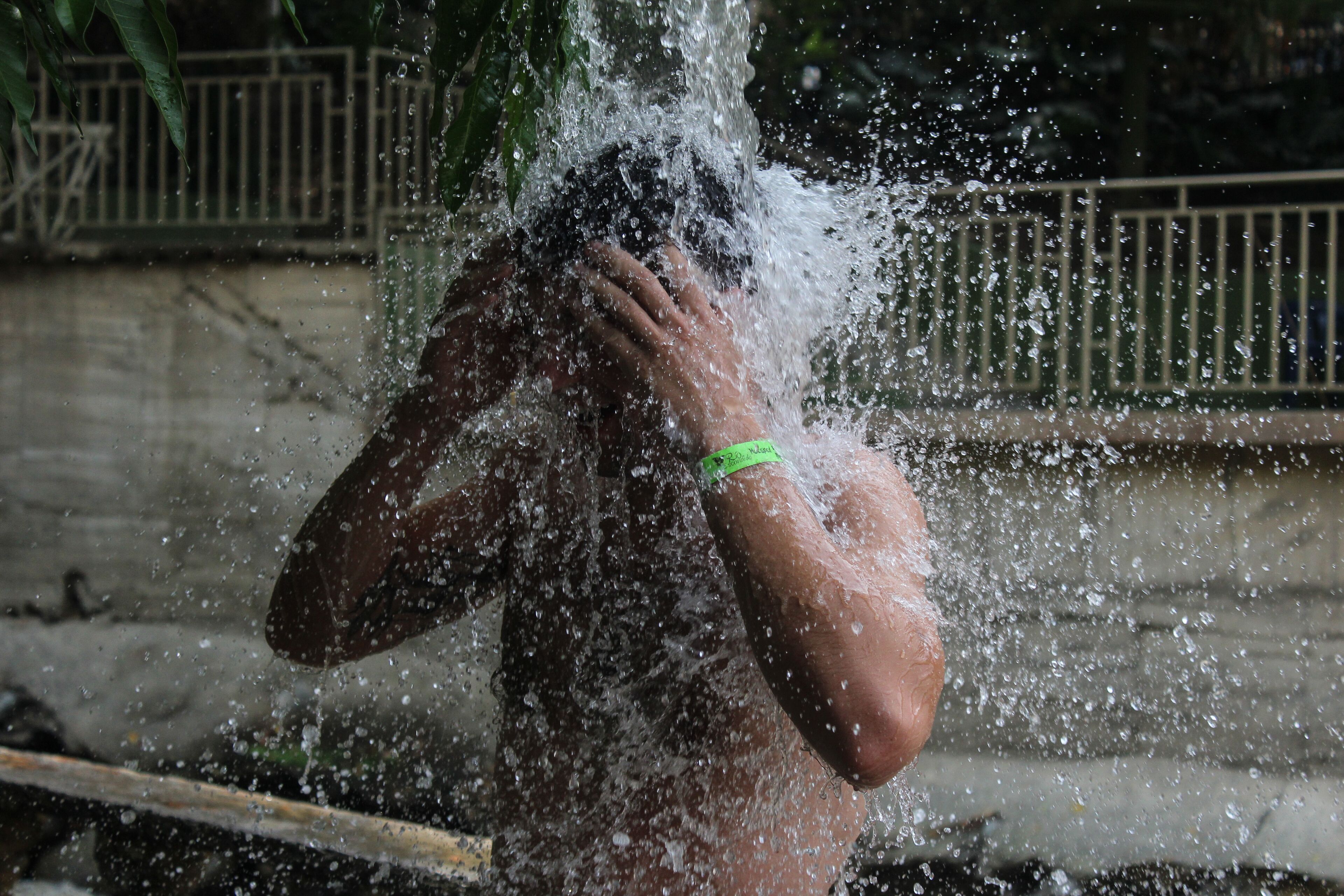 A person with water splashing around them, wearing a green wristband.