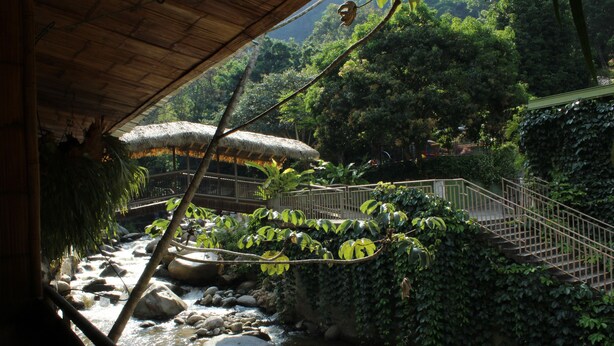 A river with rocks and a bridge with a railing. - Hostería Río Escondido (San Jerónimo)