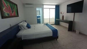 A hotel room with a bed, a TV, a painting, and a bathroom visible through an open door. - Hostería Río Escondido (San Jerónimo)