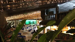 An indoor dining area with tables and chairs, a bar area, and a view of the outside. - Hostería Río Escondido (San Jerónimo)
