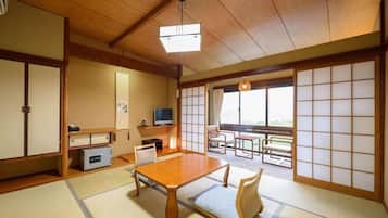 Een traditionele Japanse kamer met tatami vloeren, een lage tafel, een bank en verschuifbare deuren.