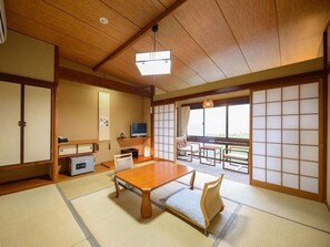 Estada tradicional japonesa amb tatami, una taula baixa, un sofà i portes corredisses.