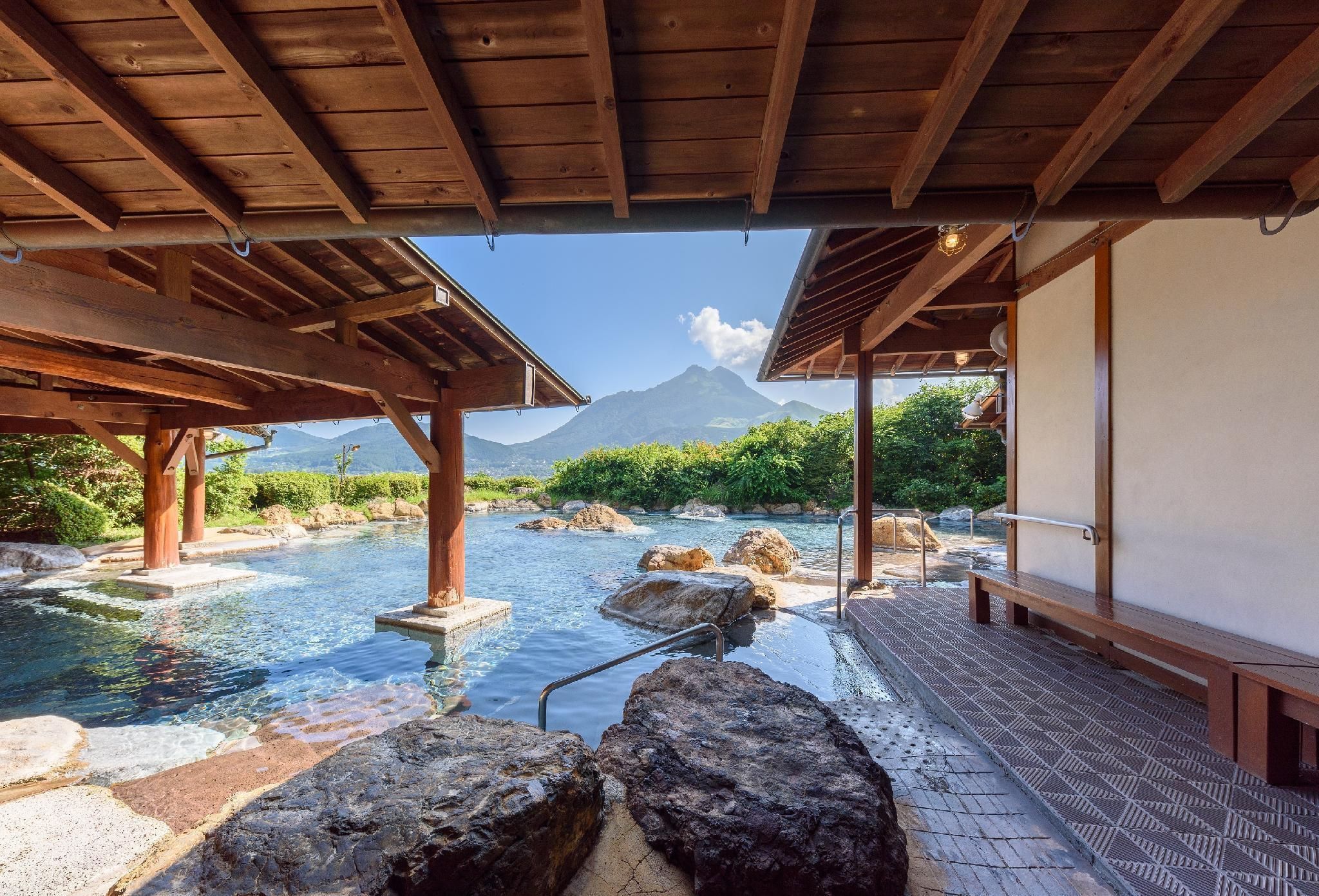 A traditional Japanese onsen with wooden structures, a stone pathway, and a mountain view.