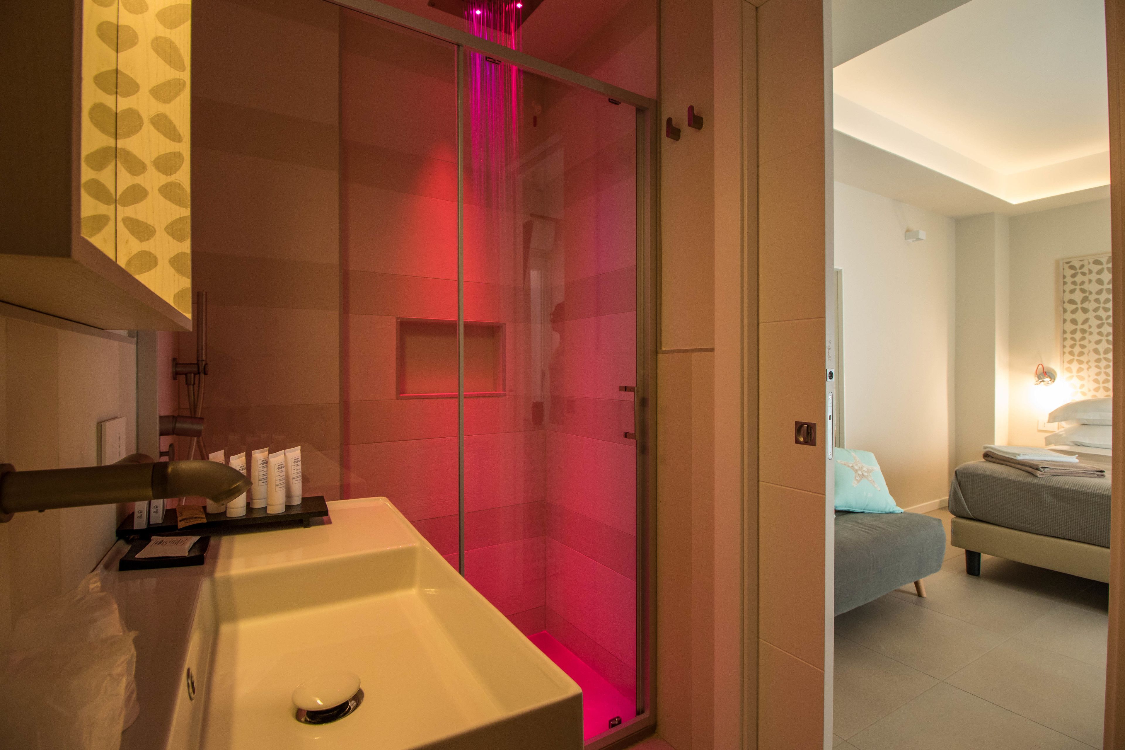 A modern bathroom with a glass-enclosed shower, a white sink, and toiletries on the counter.